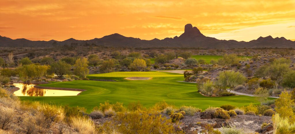 Golf course at sunset with mountain backdrop and water hazard in the luxurious Wickenburg Ranch.